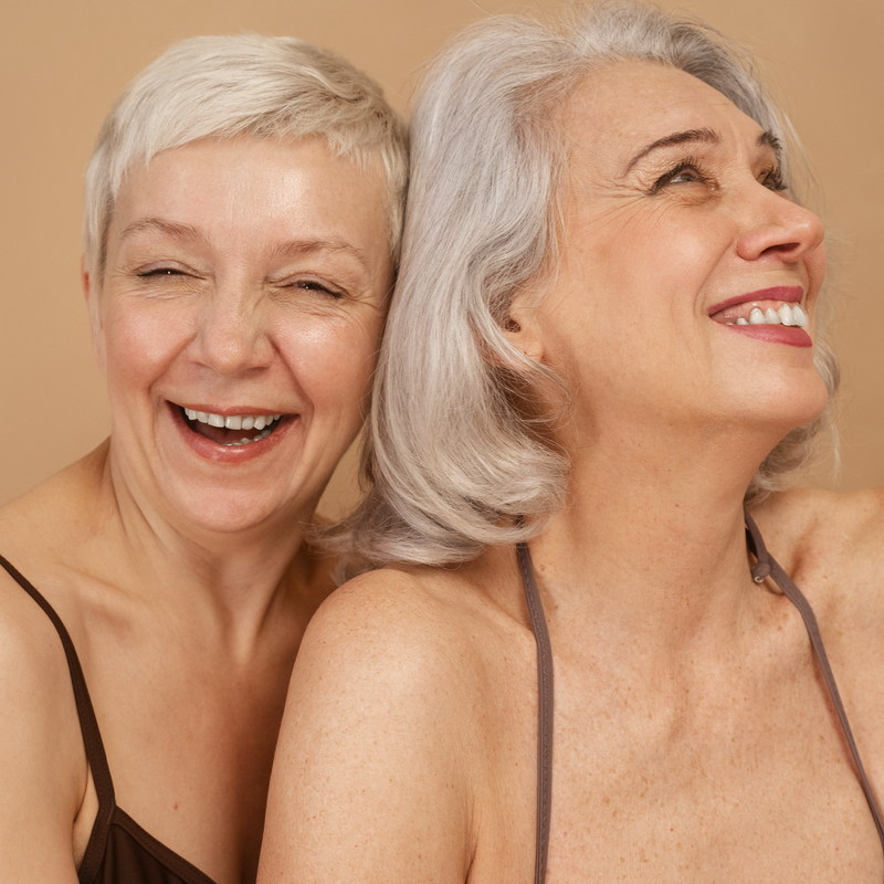 Two women with gray hair smiling against a beige background