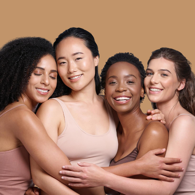 Four women of different ethnicities hugging each other against a beige background