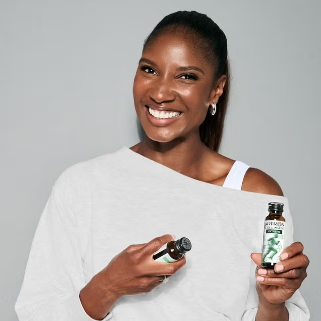 Woman holding two bottles of a skincare product against a gray background